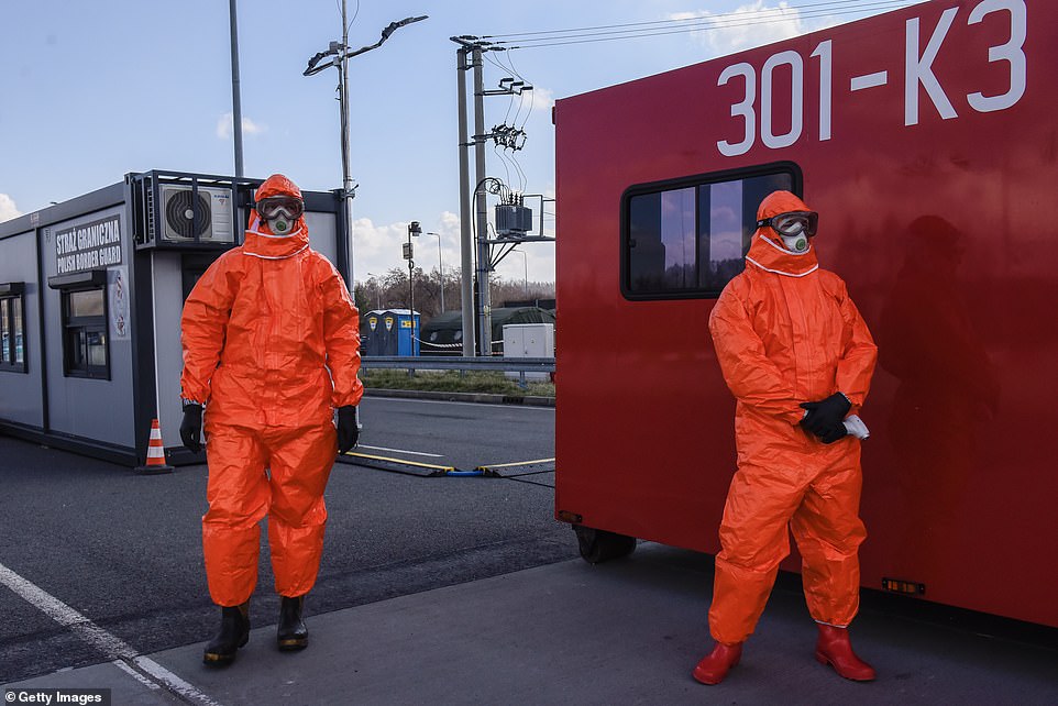 Health workers wear a protective masks and suits near the Polish-Czech border.jpg