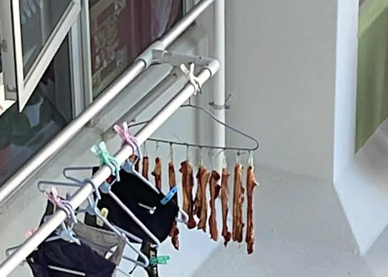 2 約10條臘肉掛在一個衣架上，與一批內衣褲一起曬，簷篷沾滿油漬。.jpg.jpg
